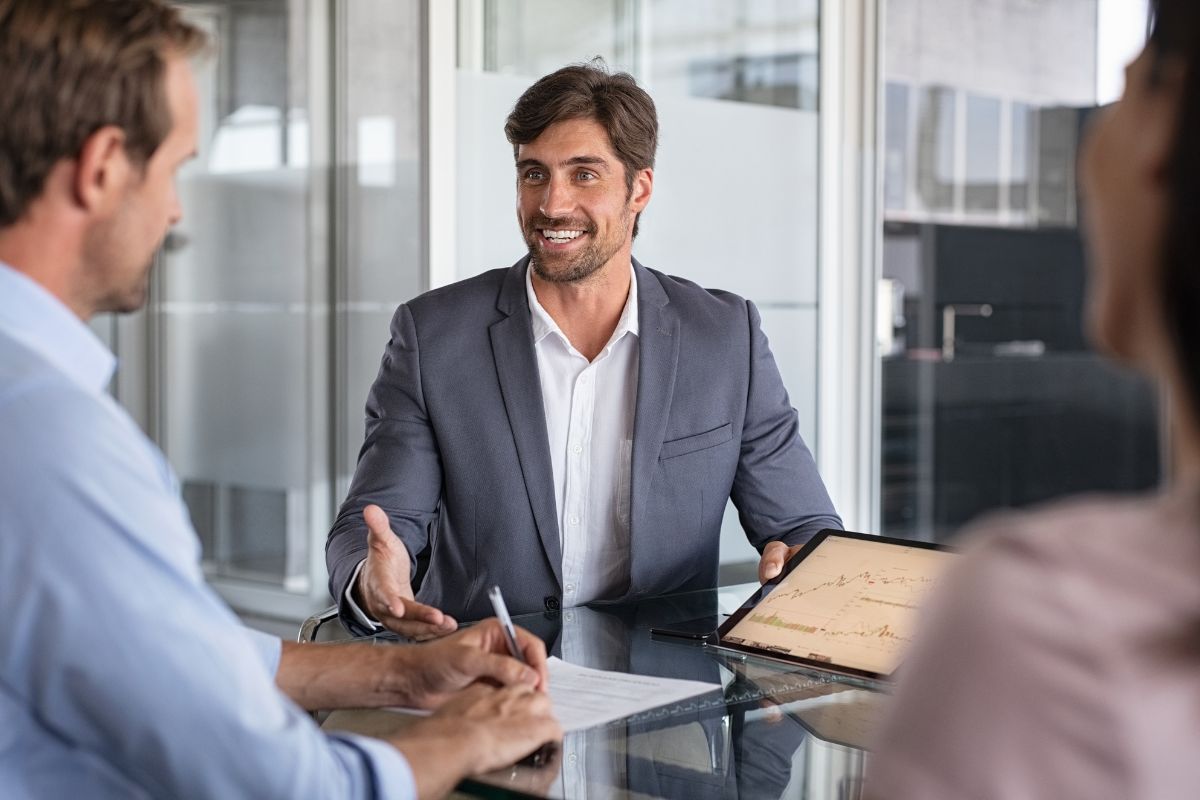 The picture shows a couple and a man in a suit holding a tablet device and explaining it to them which refers to how working with financial advisors can help you avoid mistakes and find opportunities you might not see on your own.