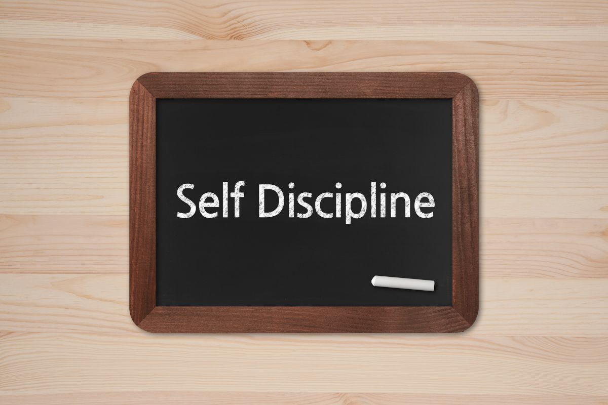 The picture shows a board with chalk and notes indicating to challenge build self-discipline help you become stronger with money.