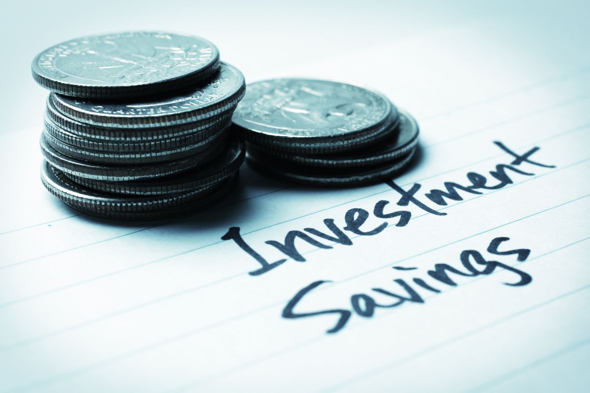 The image shows coins and a piece of paper with notes which means saving and investing consistently even small amounts regularly can add up over time.