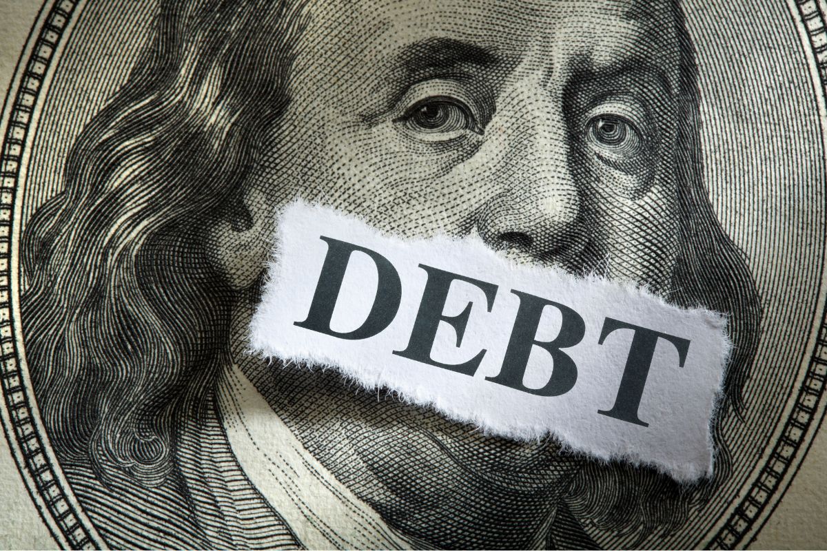 The photo shows a dollar bill icon and a piece of paper with a note that states that eliminating and avoiding interest debt keeps your finances strong and gives you more control over your money.