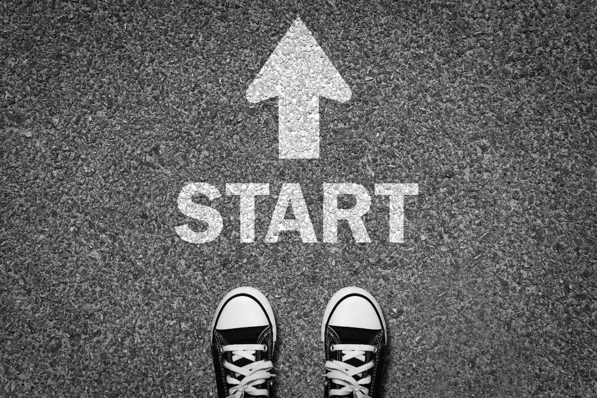 The photo shows a road with a note an arrow and a pair of shoes indicating that everyone starts at zero to become a millionaire, take control of their money, grow savings, and work toward financial independence.