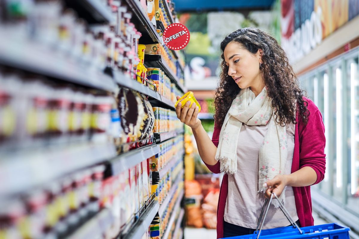 The photo shows product displays and a girl holding a basket while picking up a product referring to purchases store-brand instead of name brands help stretch your grocery budget without sacrificing taste or nutrition.