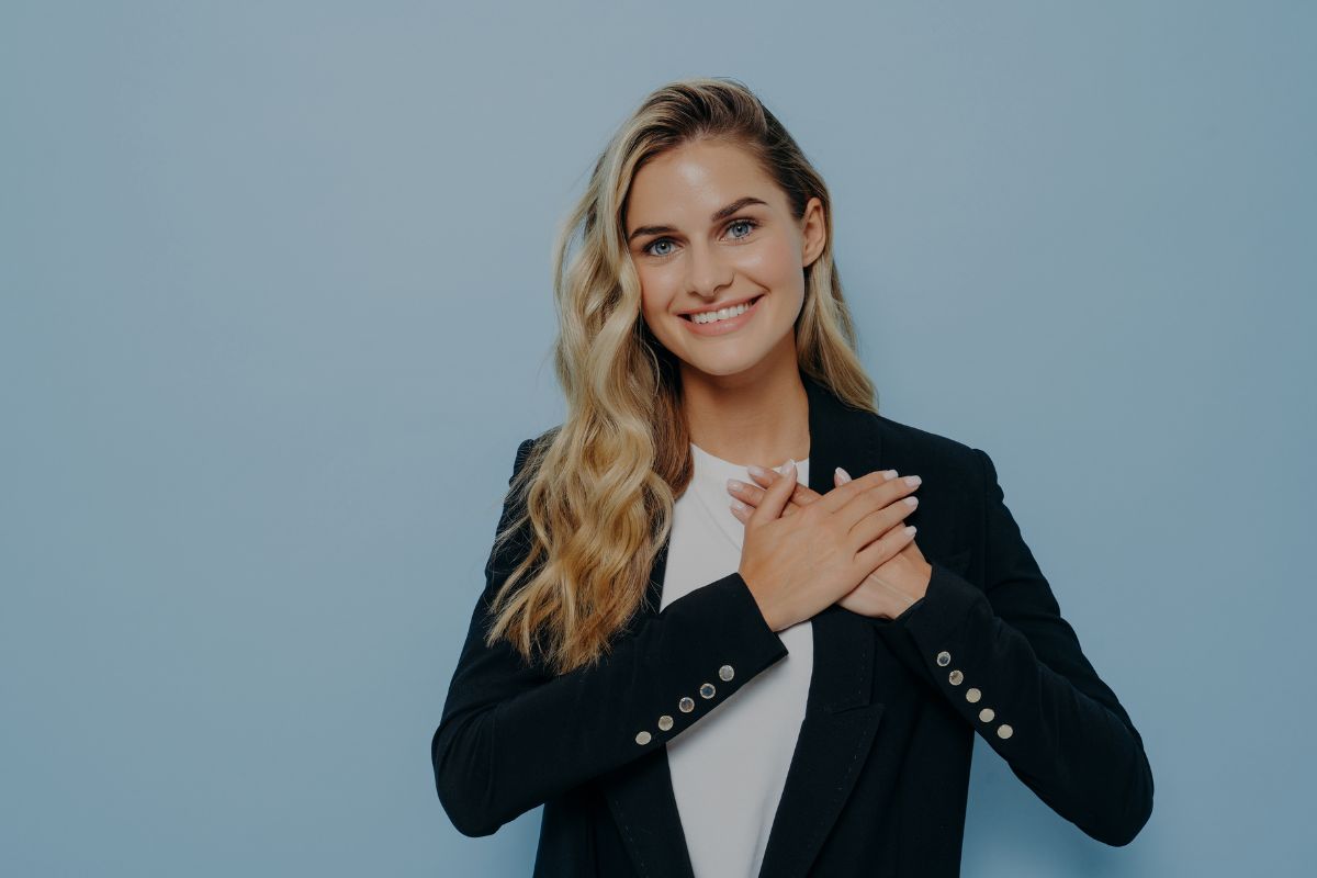 The photo shows a girl putting her hands on her chest which refers to the benefits that often extend beyond the challenge and can change how you handle money for life.