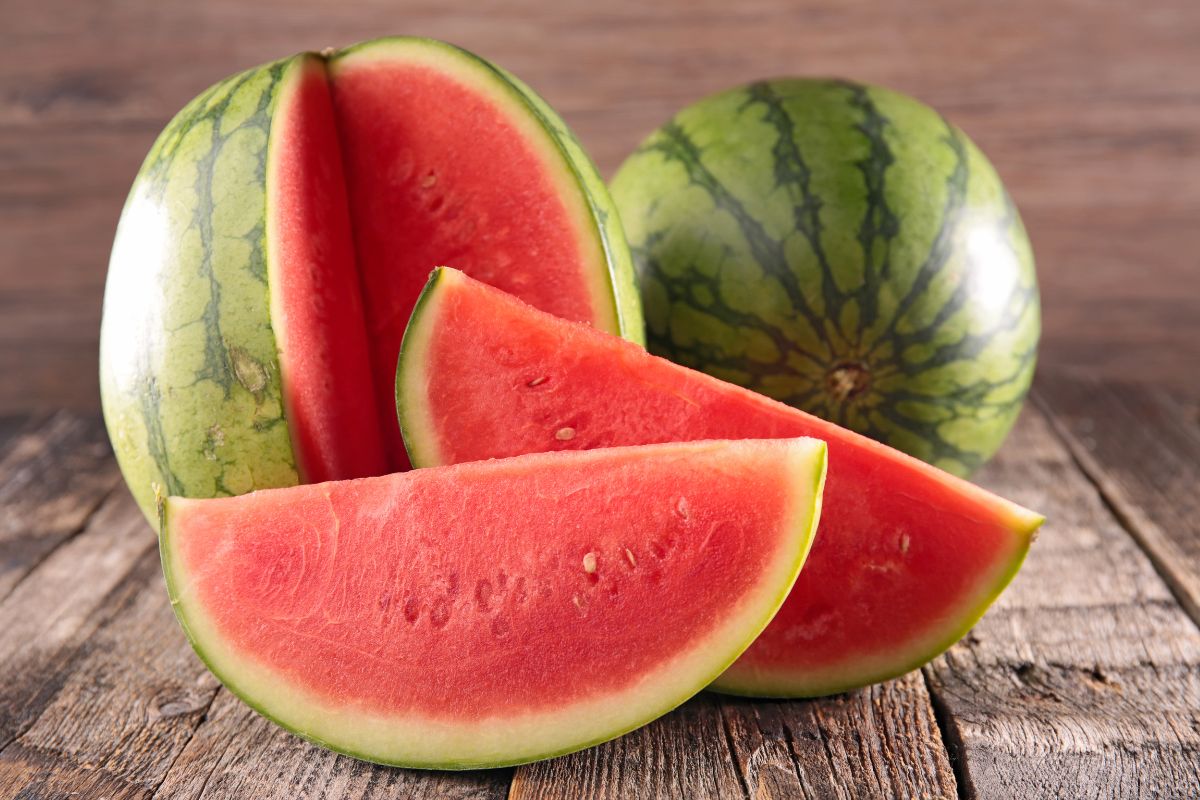 The picture shows sliced and whole watermelon at the table indicating that buying whole foods instead of pre-cut saves money and gives you more food for the same price.