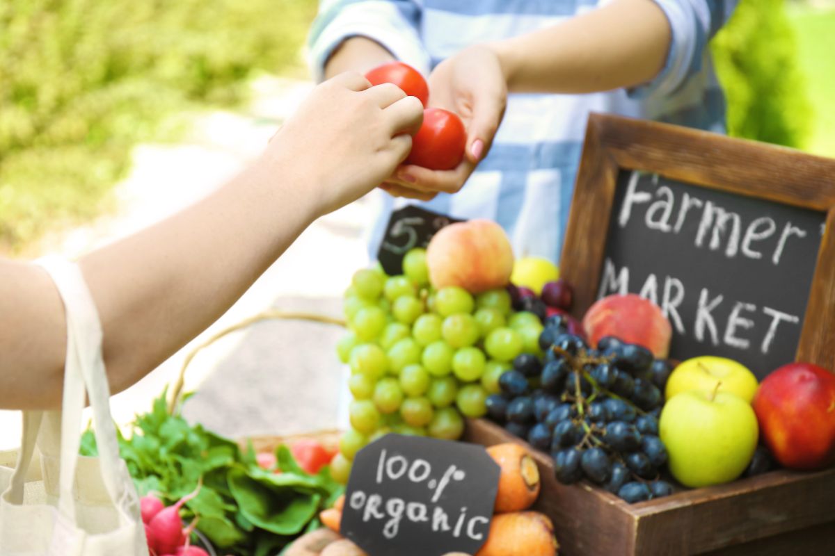 The picture shows a woman buying at the local market.