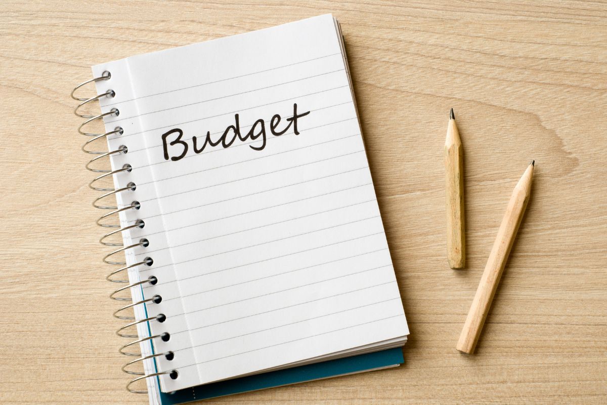 A picture of pens and a notebook with budget written.
