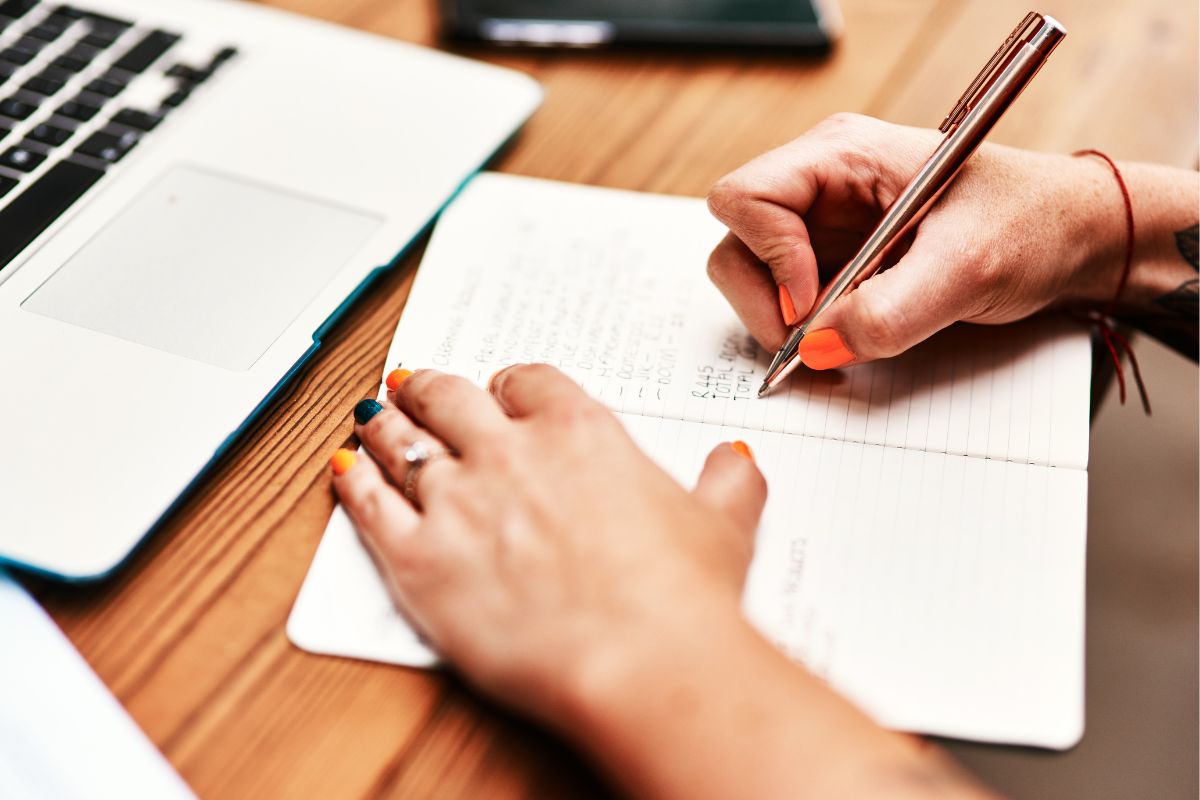 The photo of a woman's hand and writing in a notebook.