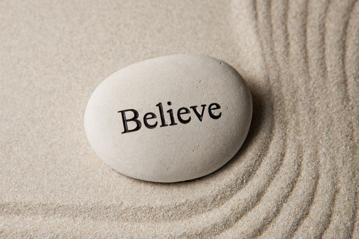 The picture shows white sand and a white stone with a note which means believe that financial abundance is possible for you and make a better choice that brings more money your way.