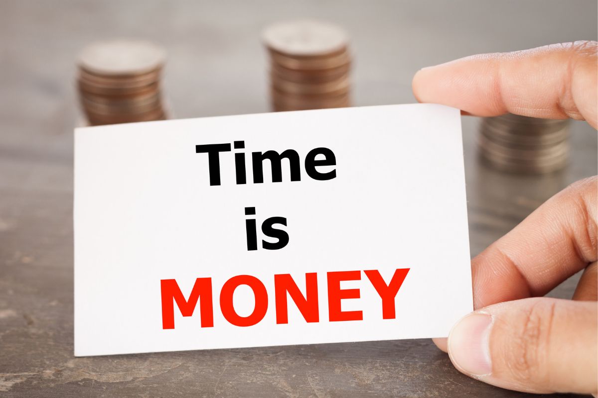 The image shows coin stocks and a man's hand holding a piece of paper with notes indicating that using positive money affirmations daily is a simple but powerful way to attract more wealth into your life.
