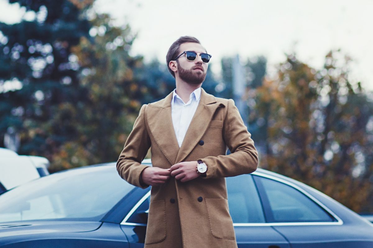 The image is about a car and a man in a suit with confidence referring to acting as if you are already financially successful and money starts moving in your favor.