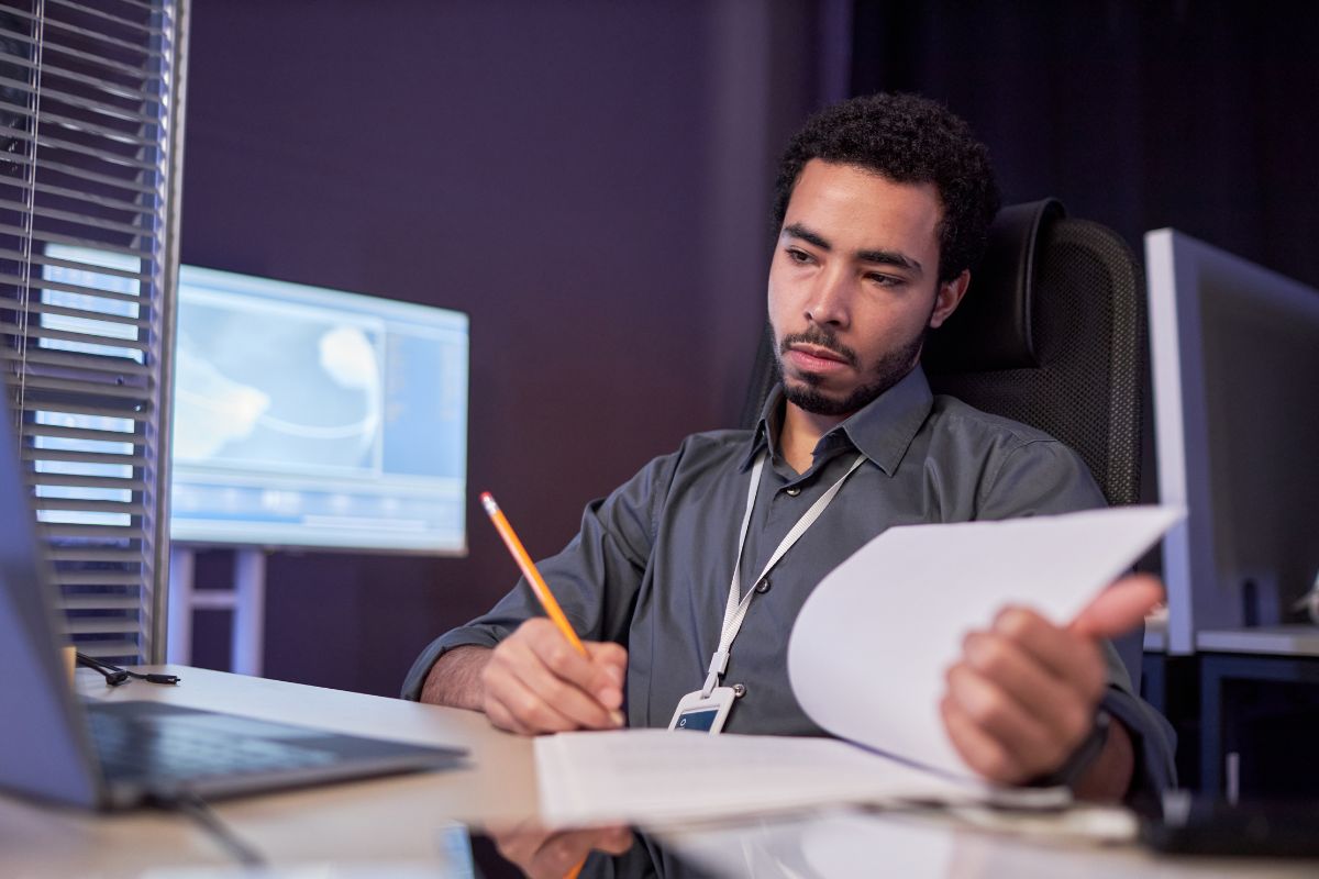 The photo tells about a man writing on paper while looking at the laptop referring to data scientists helping businesses understand numbers and trends and could be a strong career choice.