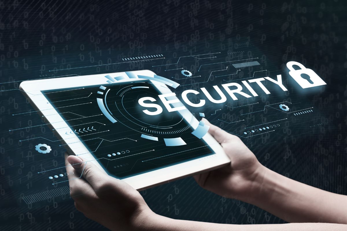 The photo tells about a girl's hand holding a tablet device with a screen display and a visual note and icons which refers to cybersecurity analysts keeping online data safe from hackers and working from home.