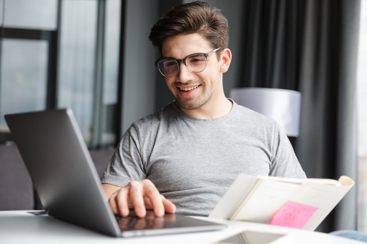 The image tells about a man using a laptop while holding a paper which refers to a product manager helping companies plan, develop, and improve products which is a good job for remote work.