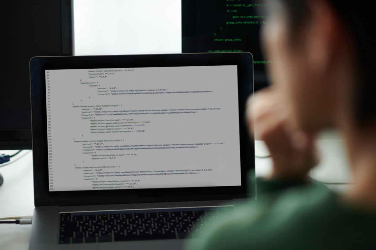 The photo shows a man looking at a laptop with a screen display which means DevOps engineers help companies keep their apps and websites running smoothly and a great online job that can be done remotely.