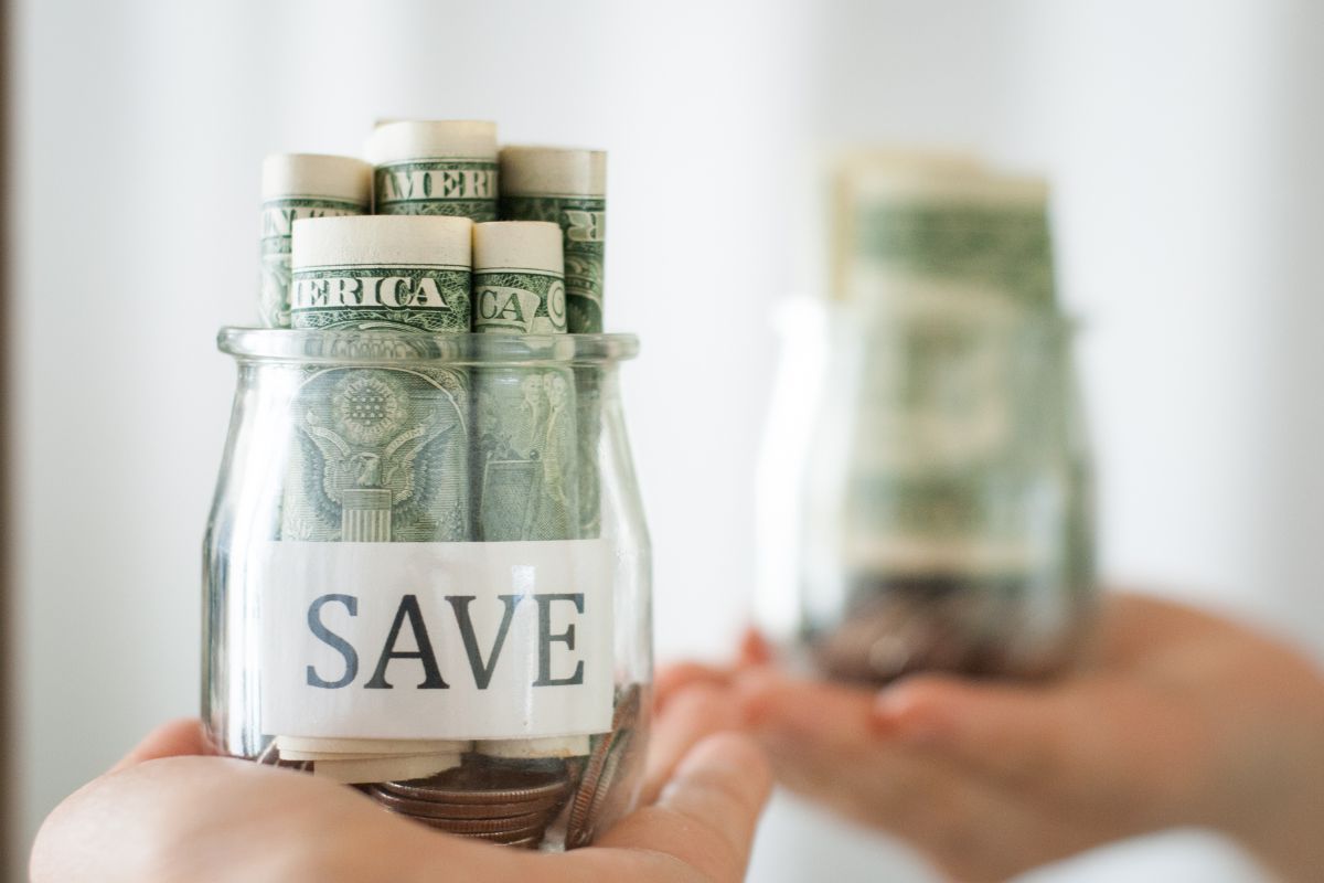 The image tells about a jar filled with dollar bills with a note and faced on the mirror referring to no spend month saves money quickly and a simple way to make your money work for you.