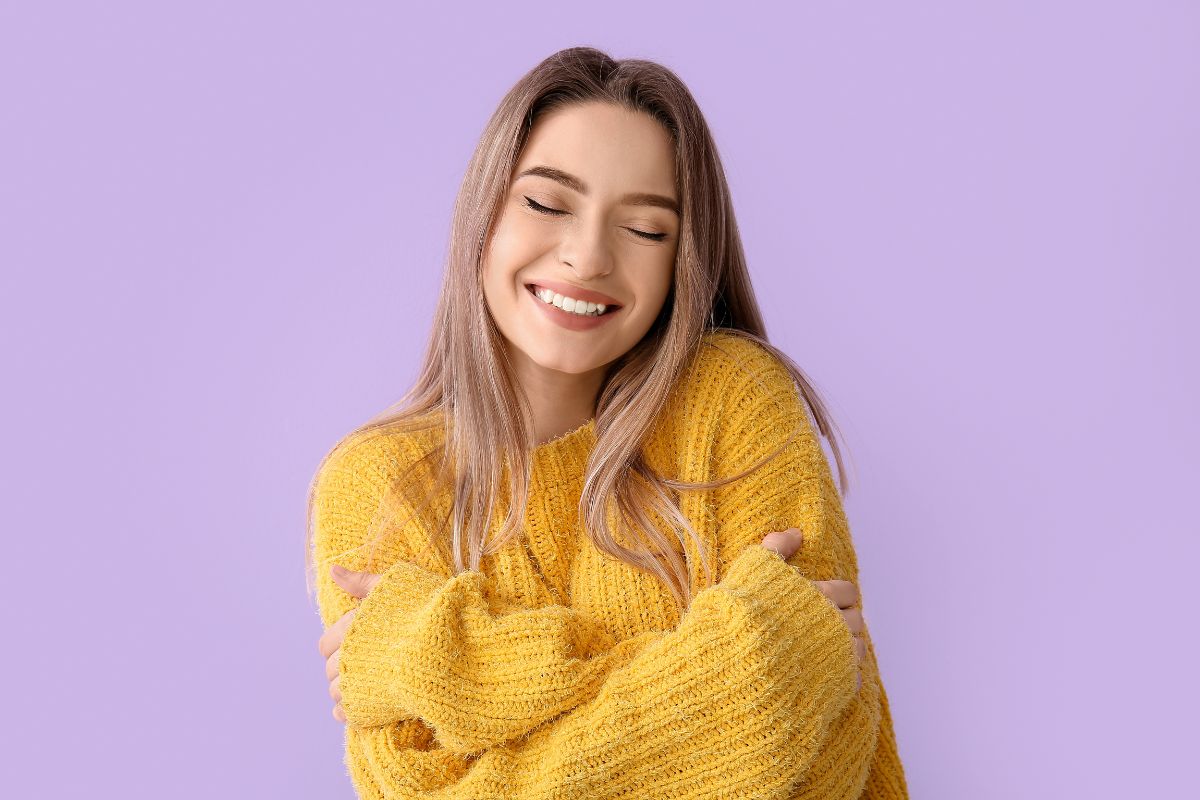 The image tells about a girl hugging herself while smiling referring to no spend month strengthens discipline and self-control that can lead to long-term financial success.