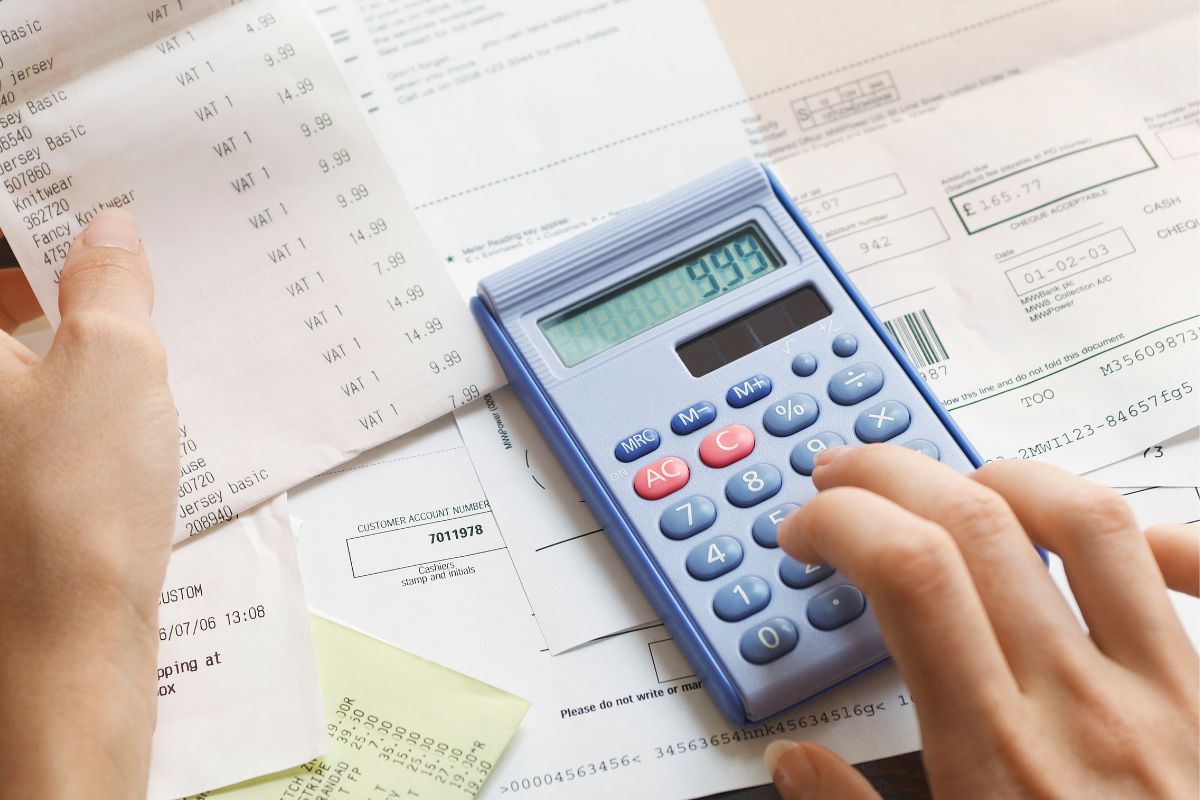 The photo shows a woman's hand calculating expenses.