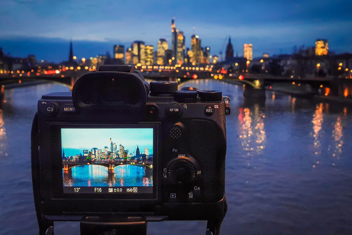The image shows a beautiful city lights, bridge, and a camera which refers to take high-quality photos and write detailed help items sell faster and for more money.