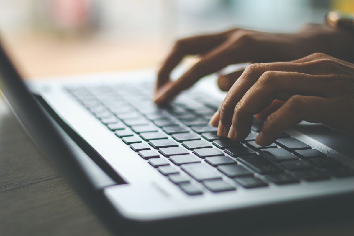 The image shows a girl's hand typing on the laptop indicating that listing items on multiple platforms for maximum visibility increases sales without needing to buy more items.