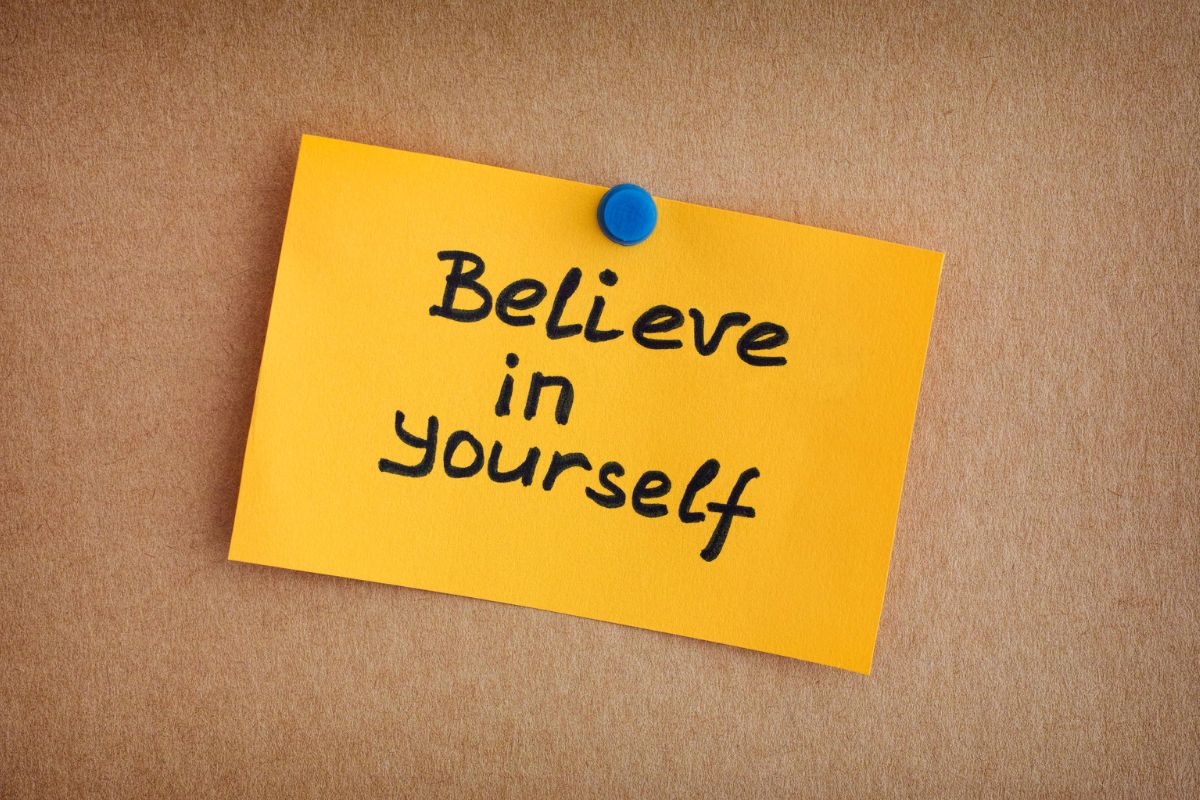 The photo shows a piece of paper with notes pinned on the wall referring to believing in your ability to reach your savings target keeps you moving forward.