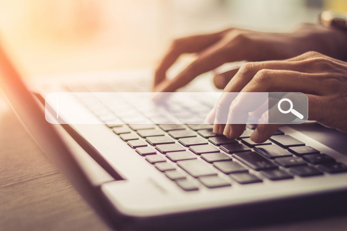 The photo tells about a girl's hand using a laptop with a search icon on the screen which refers to optimizing listing with relevant keywords for search visibility to help items show up in results.