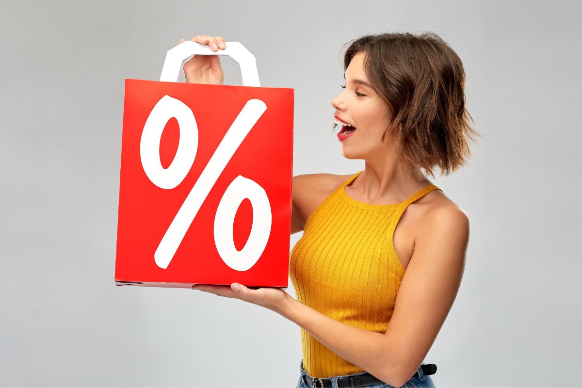 The image shows a woman holding a paper bag with a percentage sign.