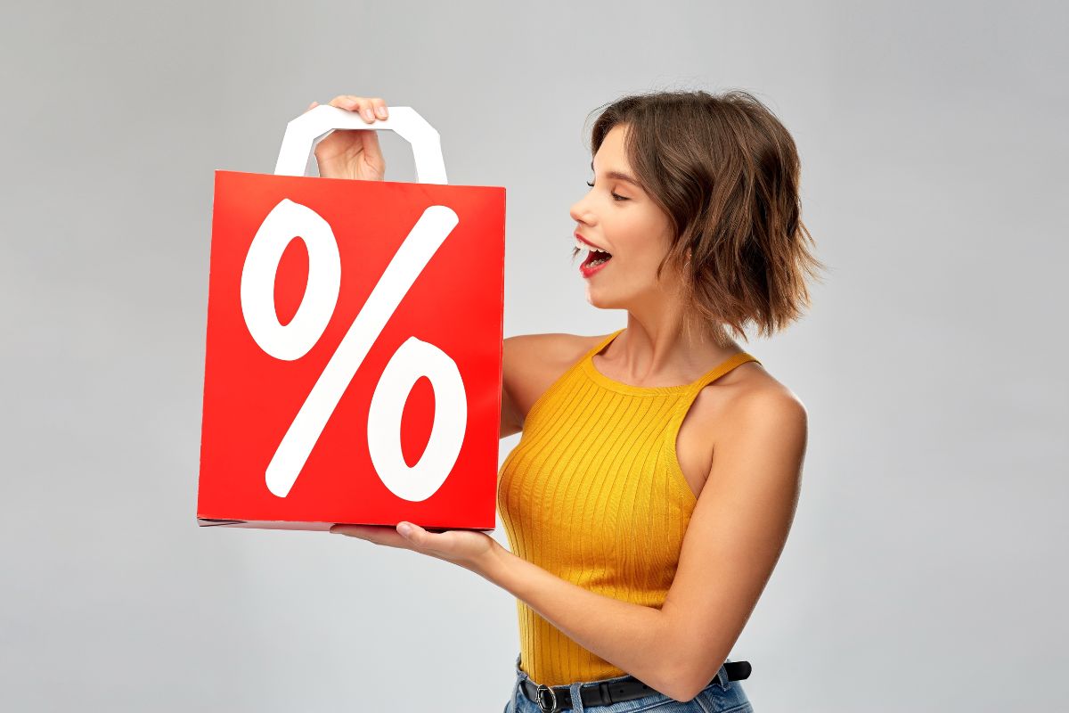 The image tells about a girl holding a bag with a percentage icon which refers to offering discounts for multiple purchases that can bring in more and clear out inventory faster.