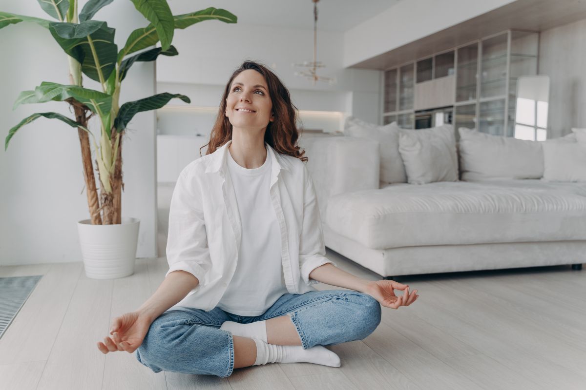 The image tells about a couch, a plant, and a girl sitting on the floor which refers to debt-free provides peace of mind and gives you confidence in your financial future.