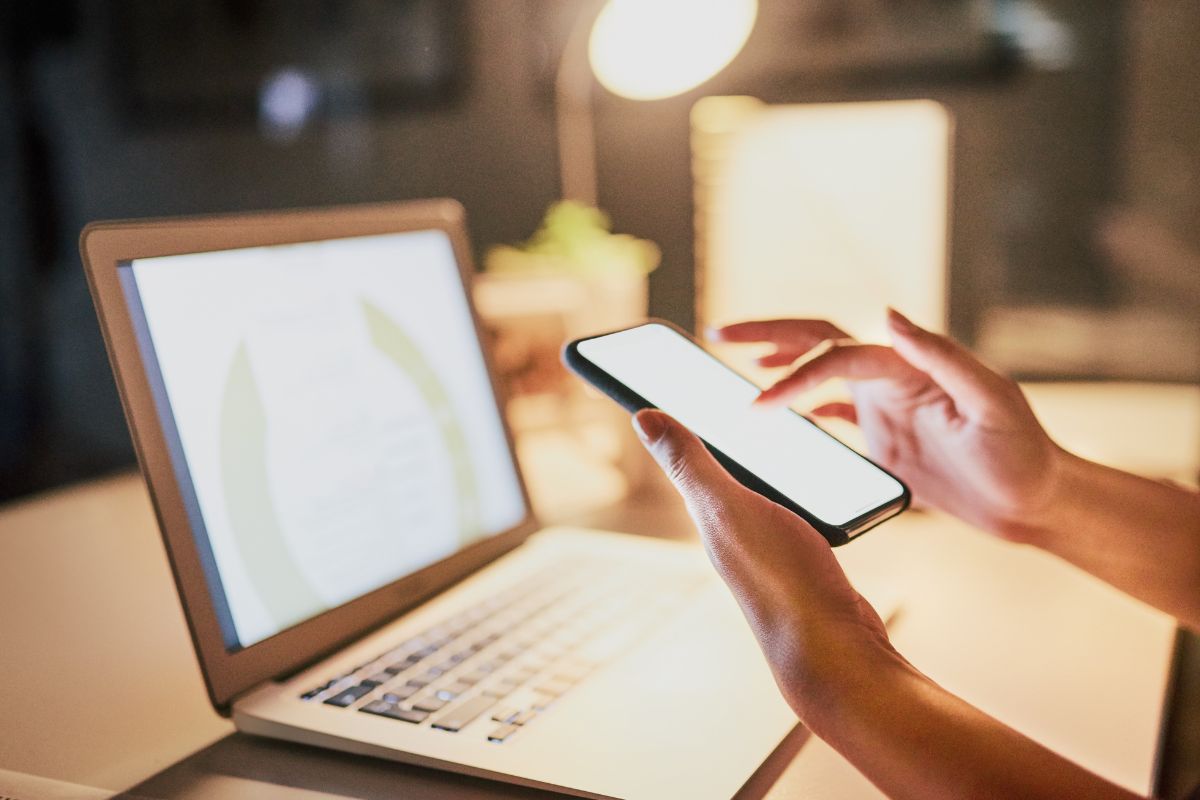 A picture shows a woman using a laptop and a phone for marketing.