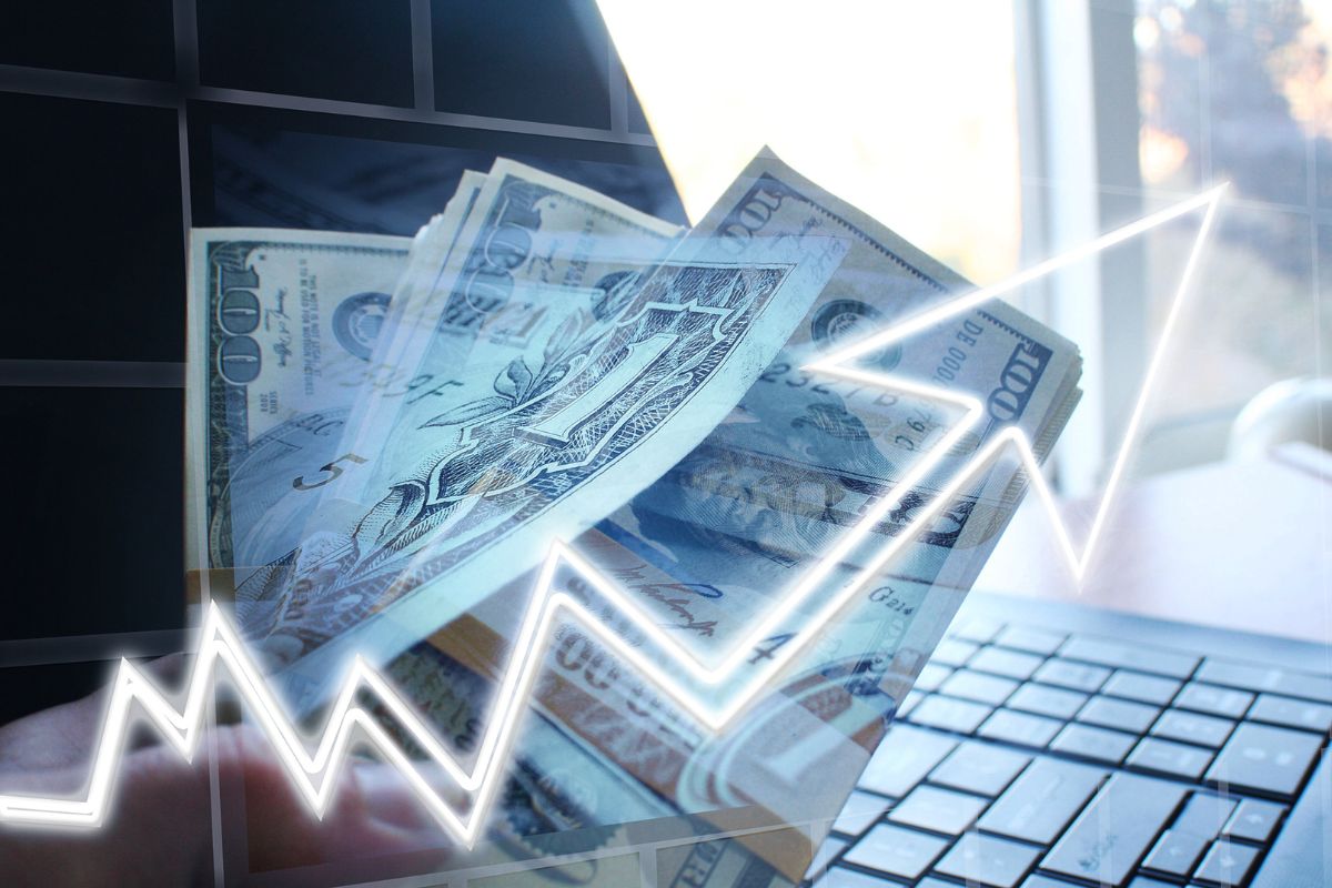 The image shows dollar bills and a laptop to diversify investments.