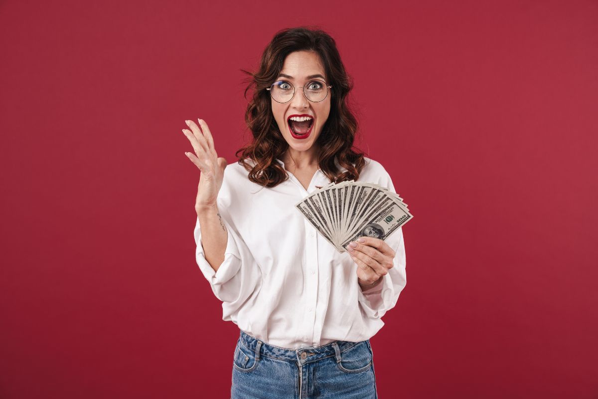 The image of a happy girl holding dollar bills which means starting by making at least 10k a month and making smart money moves to grow wealth.