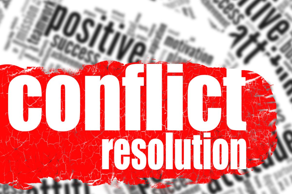 The image shows notes behind and red paint with notes indicating that conflict resolution can keep things running smoothly.