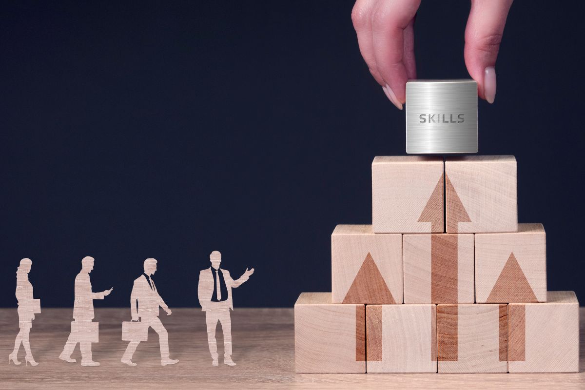 The picture shows business human figures, wooden cubes with arrows, and a girl's hand putting the last cube with notes indicating to use these high-income skills without a degree that can change your financial future.