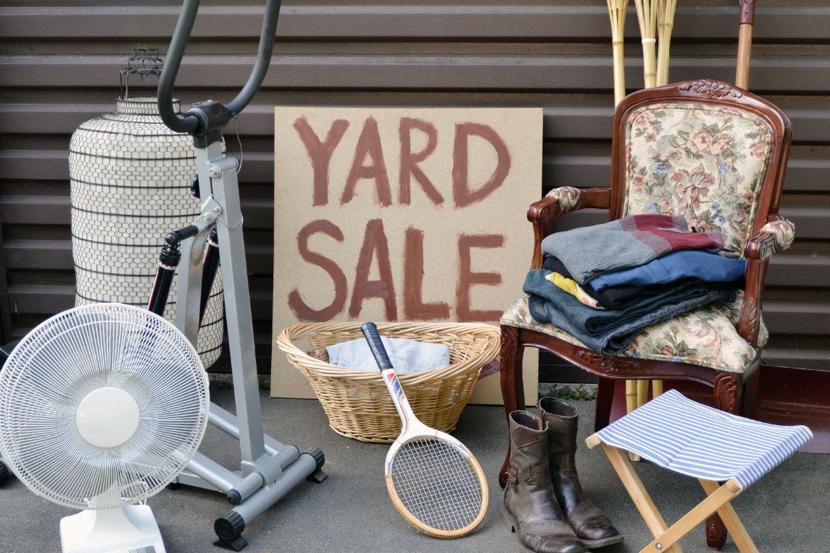 The picture shows chairs, an electric fan, a rocket, a pair of boots, a basket, clothes, and a board with notes referring to hosting a reverse yard sale to help others without spending money and connecting with people.