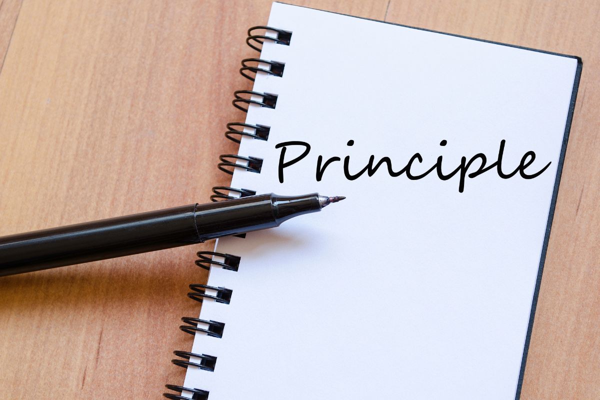 The image tells about a pen and notebook with notes indicating to core principles of FIRE help people reach a point when they no longer need to work just to pay bills.
