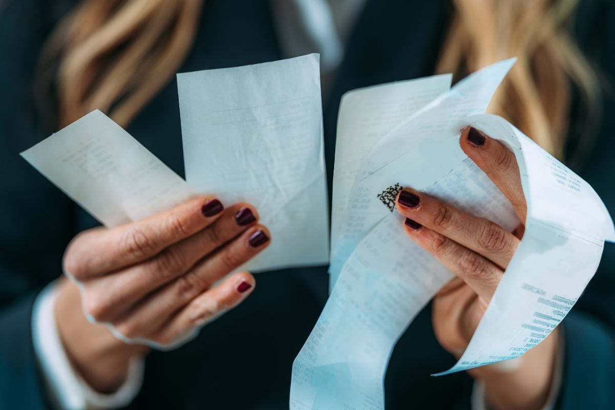 The picture tells about a girl's hand holding receipts which means that recognizing common spending environments can help avoid financial mistakes.