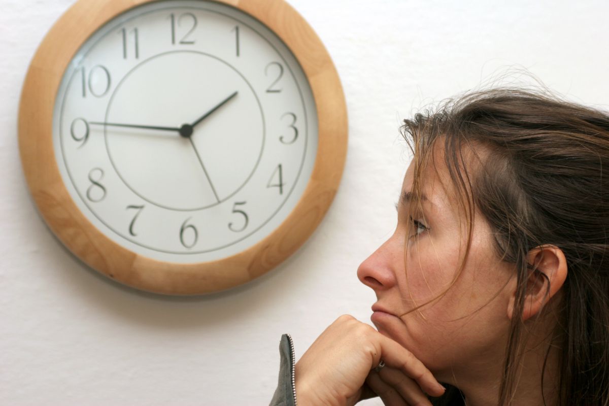 The photo shows a girl looking at the clock which means that implementing a 24-hour rule before making non-essential purchases can help you save money without feeling like you're missing out. 