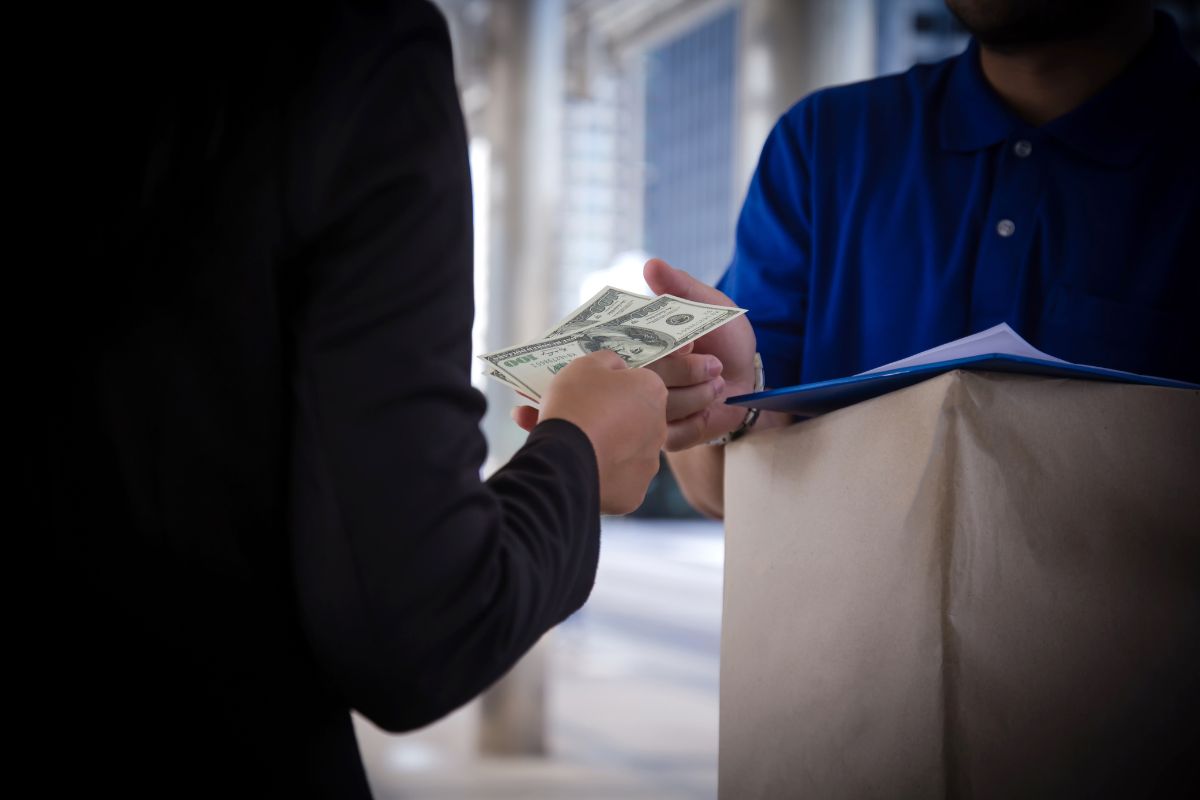 The picture tells about a delivery man with a clipboard who received money from the customer which refers to using cash instead of credit cards to help you control your budget and avoid debt.