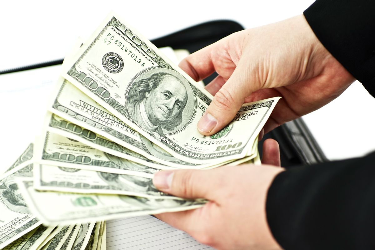 The image shows a man's hand counting money.