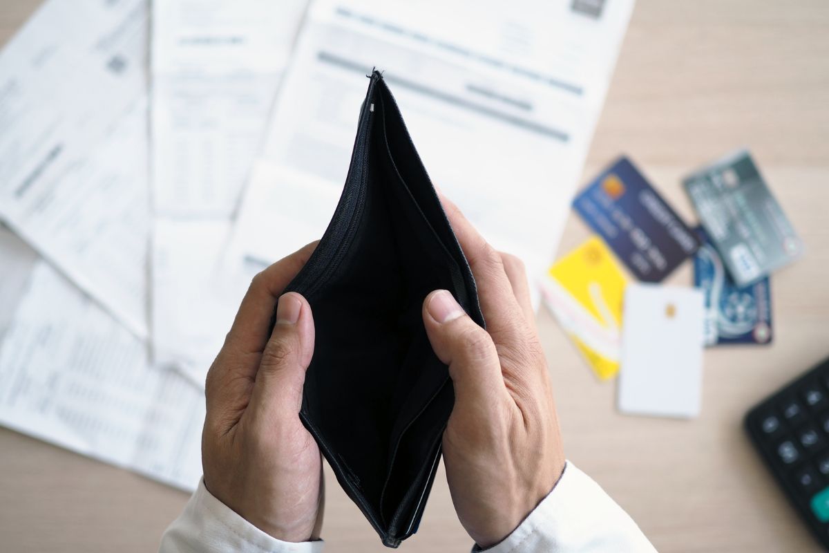The photo is about a man's hand with an empty wallet and debt.