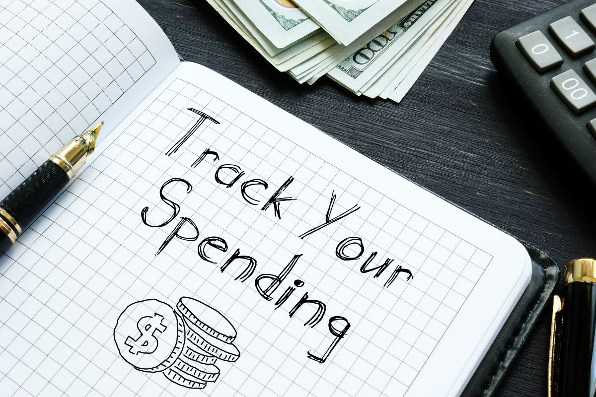 The photo shows a notebook with the Track Your Spending wording.