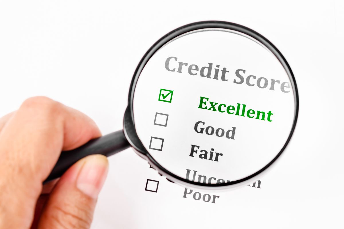 The picture shows a piece of paper with notes and a man's hand holding a magnifying glass which means that building and maintaining good credit gives you more financial opportunities and helps build long-term wealth.