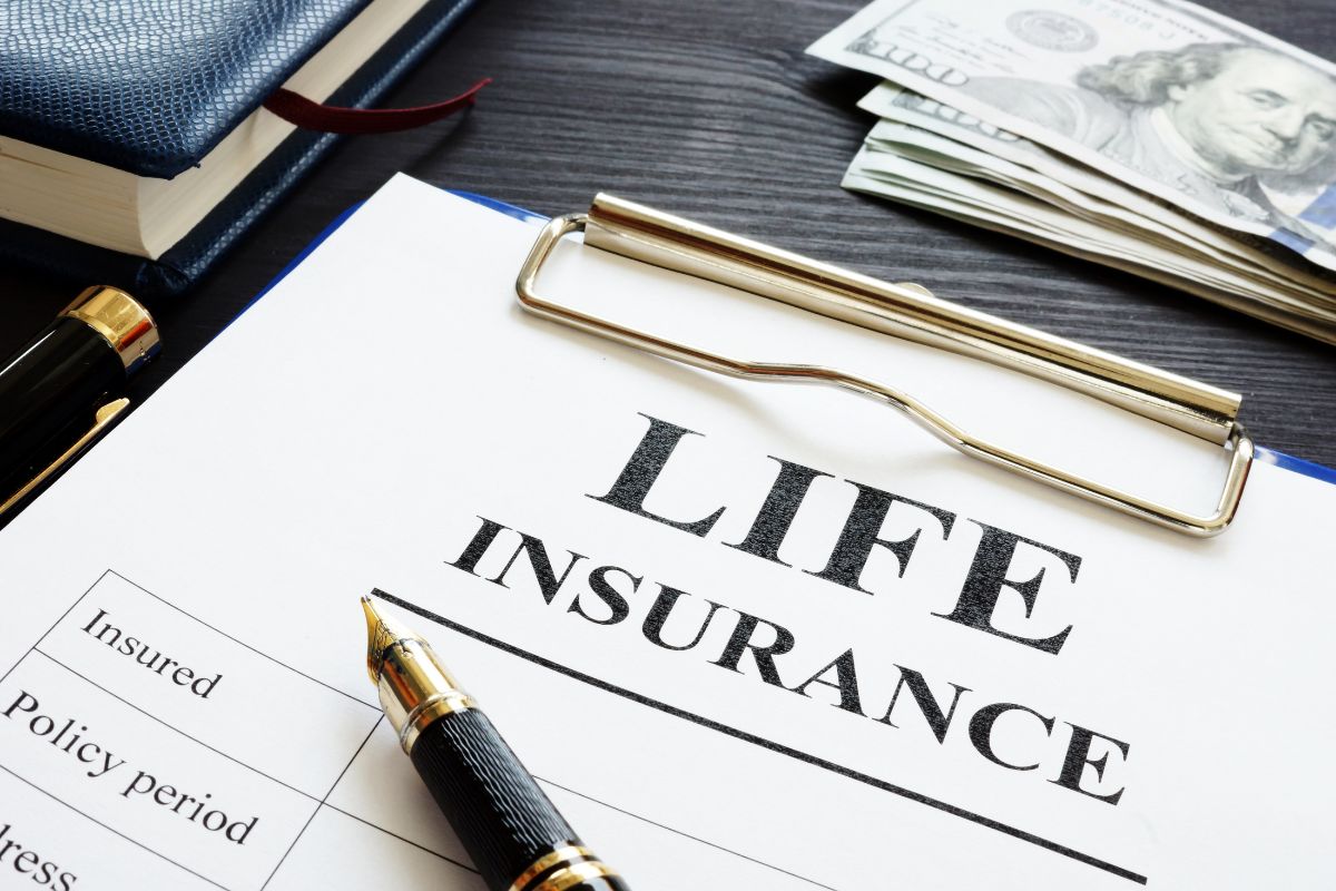 The photo shows a notebook, dollar bills, a pen, and a clipboard with notes indicating that protecting assets with insurance keeps your wealth safe for future generations.