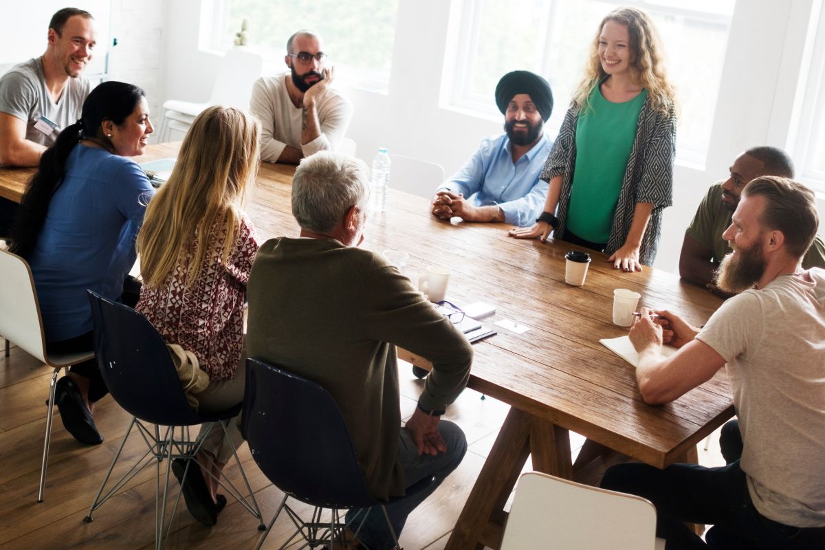 The picture tells about a group of people having a conversation over the table together which refers to network and building relationships with financially savvy individuals who can provide valuable advice and opportunities.