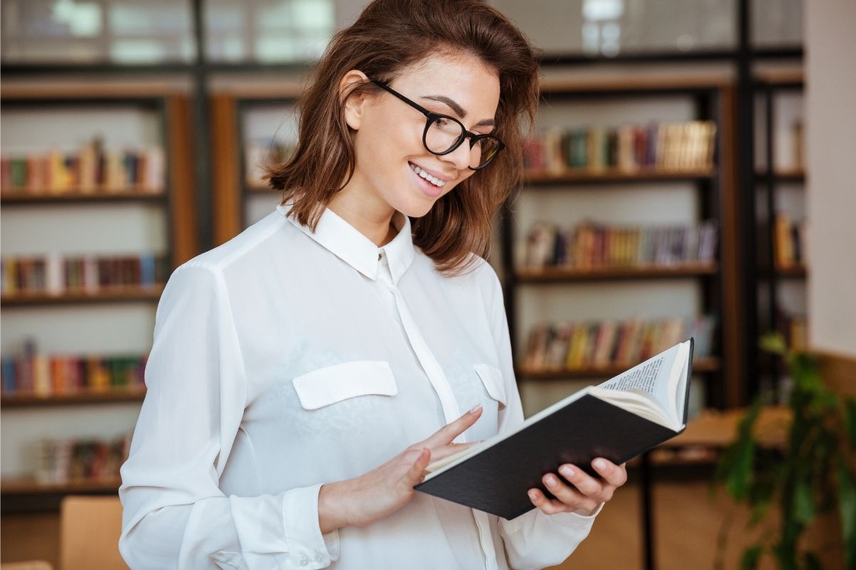 The photo shows a woman reading a book.