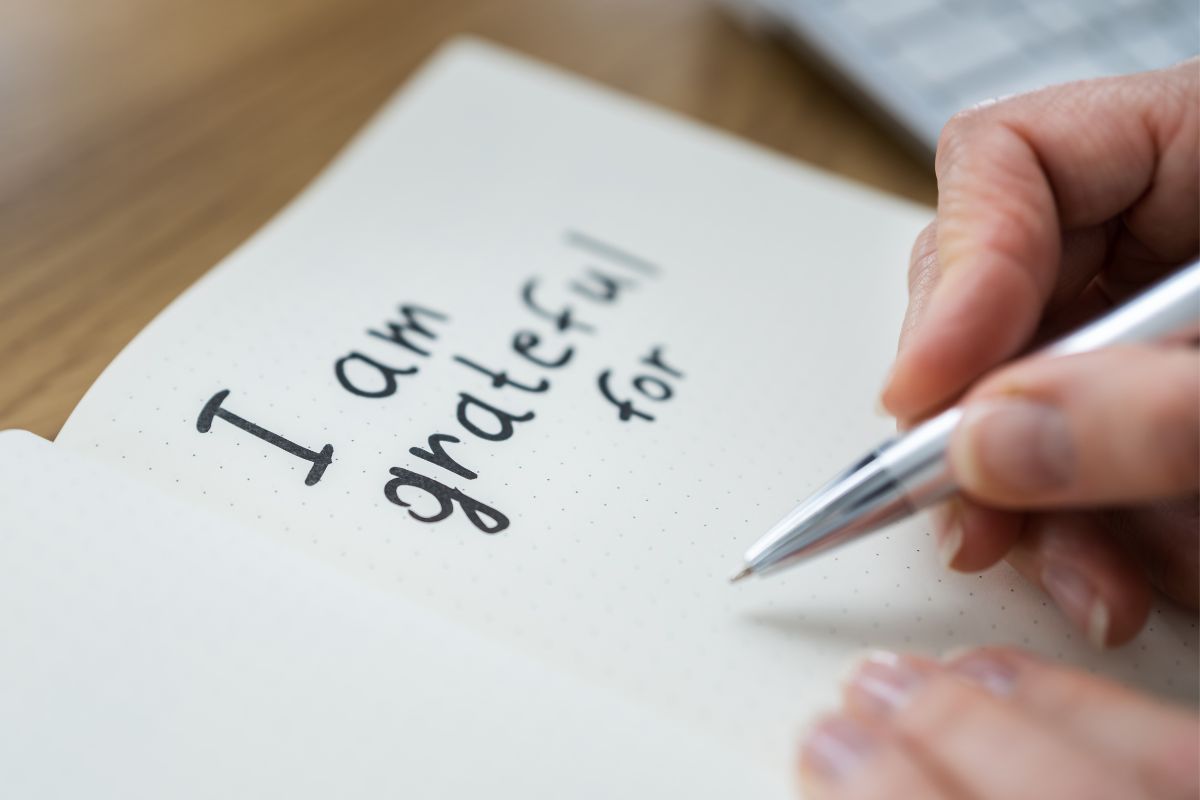 The photo shows a woman writing in a notebook.