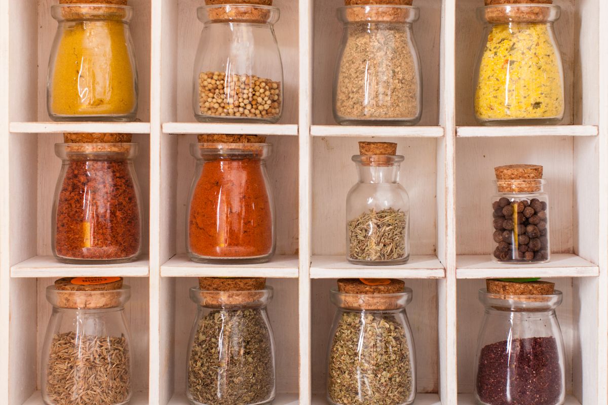 The image tells about jars with spices on the corner referring to buying bulk spices make home cooking cheaper and tastier.