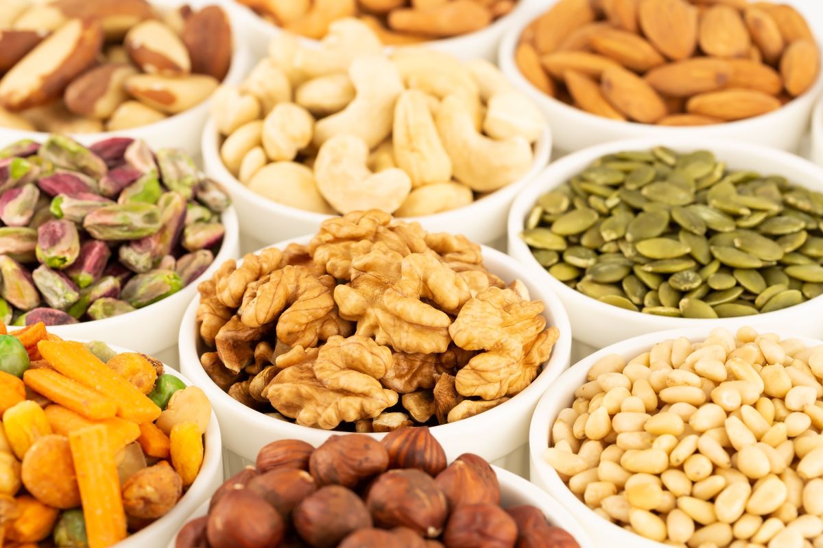The photo tells about bowls of nuts and seeds to buy nuts in bulk helps stretch your grocery budget without sacrificing quality.