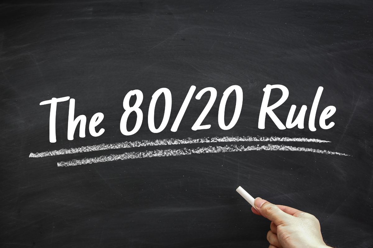 The image shows a board with notes and a girl's hand holding a chalk indicating that using the 80/20 rule aggressively helps maximize time and income without adding extra hours.