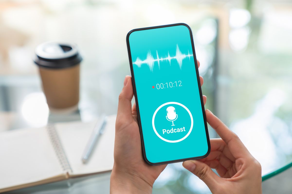 The photo shows a woman's hand listening to a podcast on her phone.